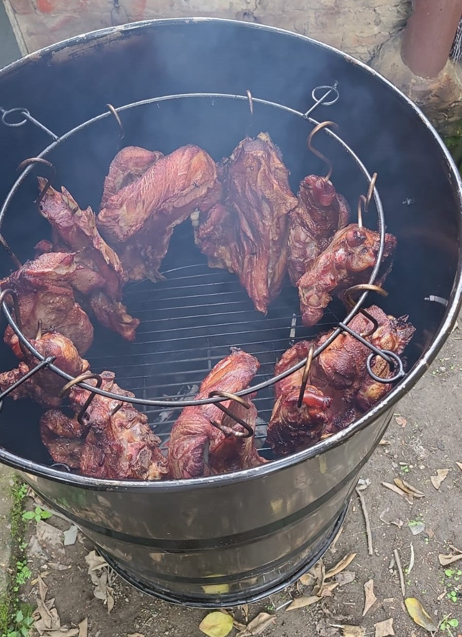 Carne asándose lentamente en barril grande – cocción uniforme y brasa constante